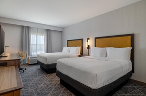 Une chambre d’hôtel avec deux lits, un bureau, une chaise et un téléviseur.