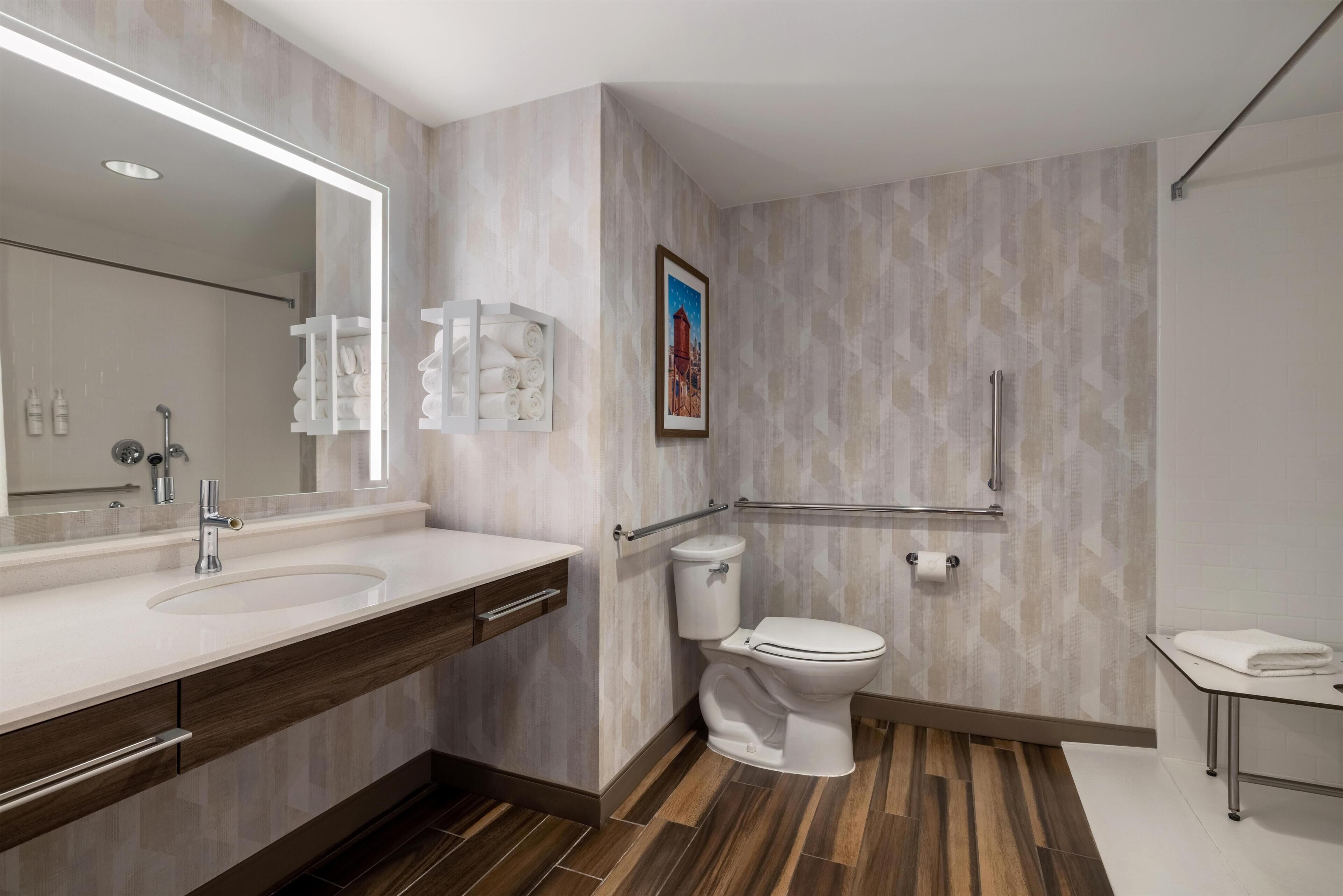 A modern bathroom with a large mirror, a sink, a toilet, and a shower area.