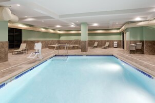 Zona de piscina de hotel con trampolín, sillas de descanso y vestuarios.