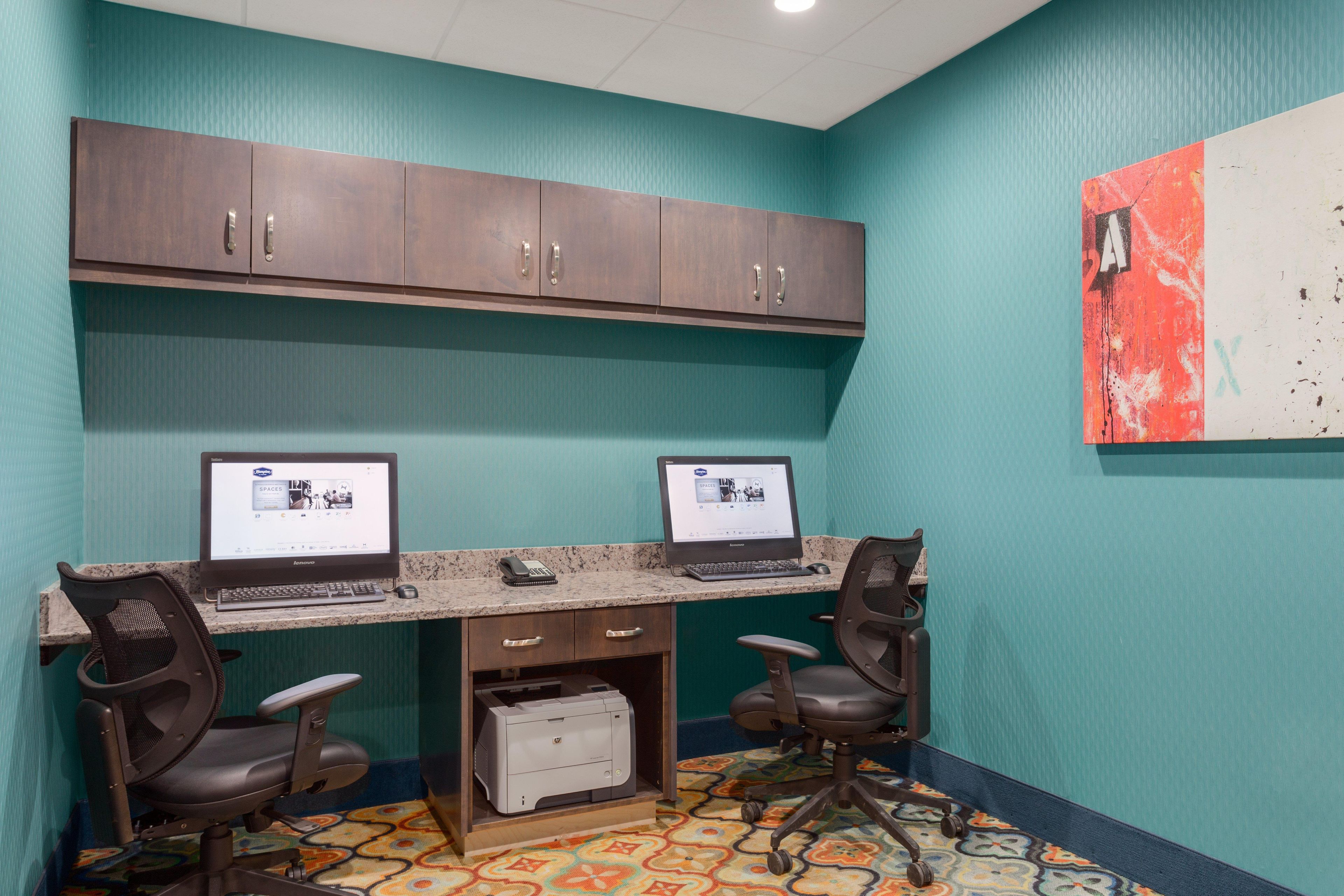 A workspace with two desks, computers, chairs, and a printer.