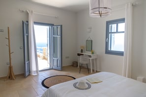 A bedroom with a bed, a desk, a chair, a window, and a view of the outdoors.