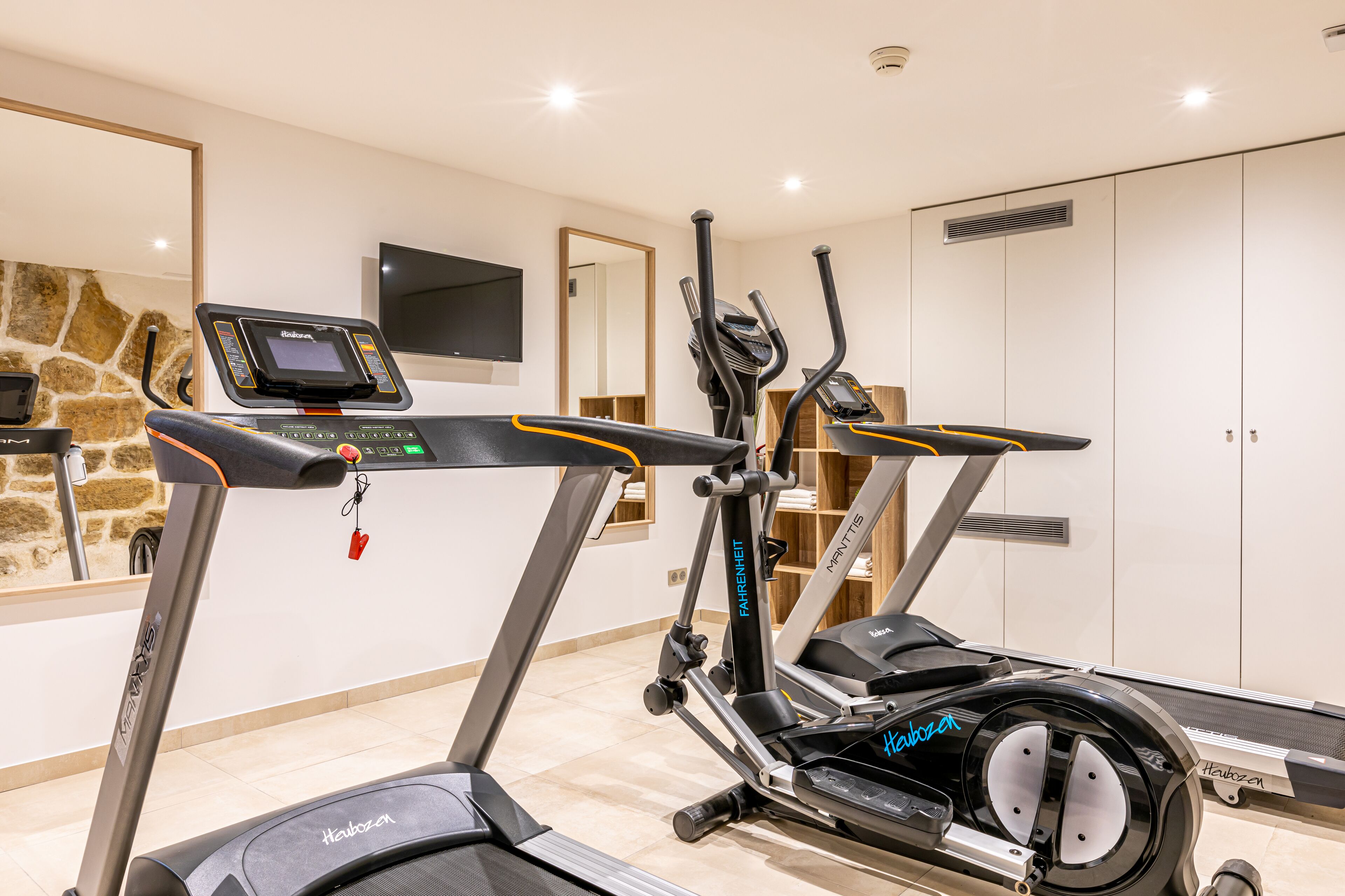 Ein Fitnessraum mit Laufbändern, einem Ergometer und einer Gewichtbank.