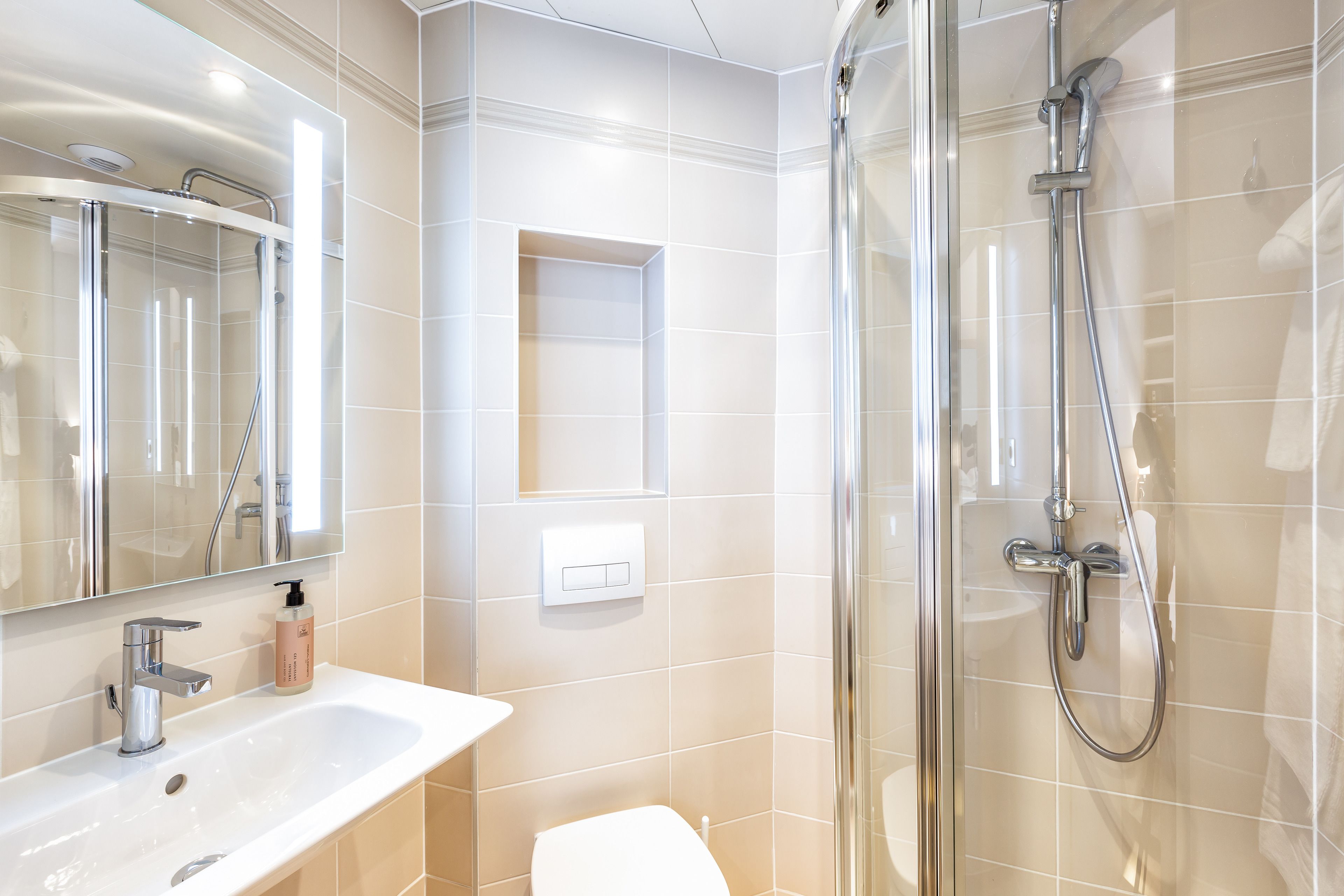 A modern bathroom with a glass-enclosed shower, a white sink, and a mirror.