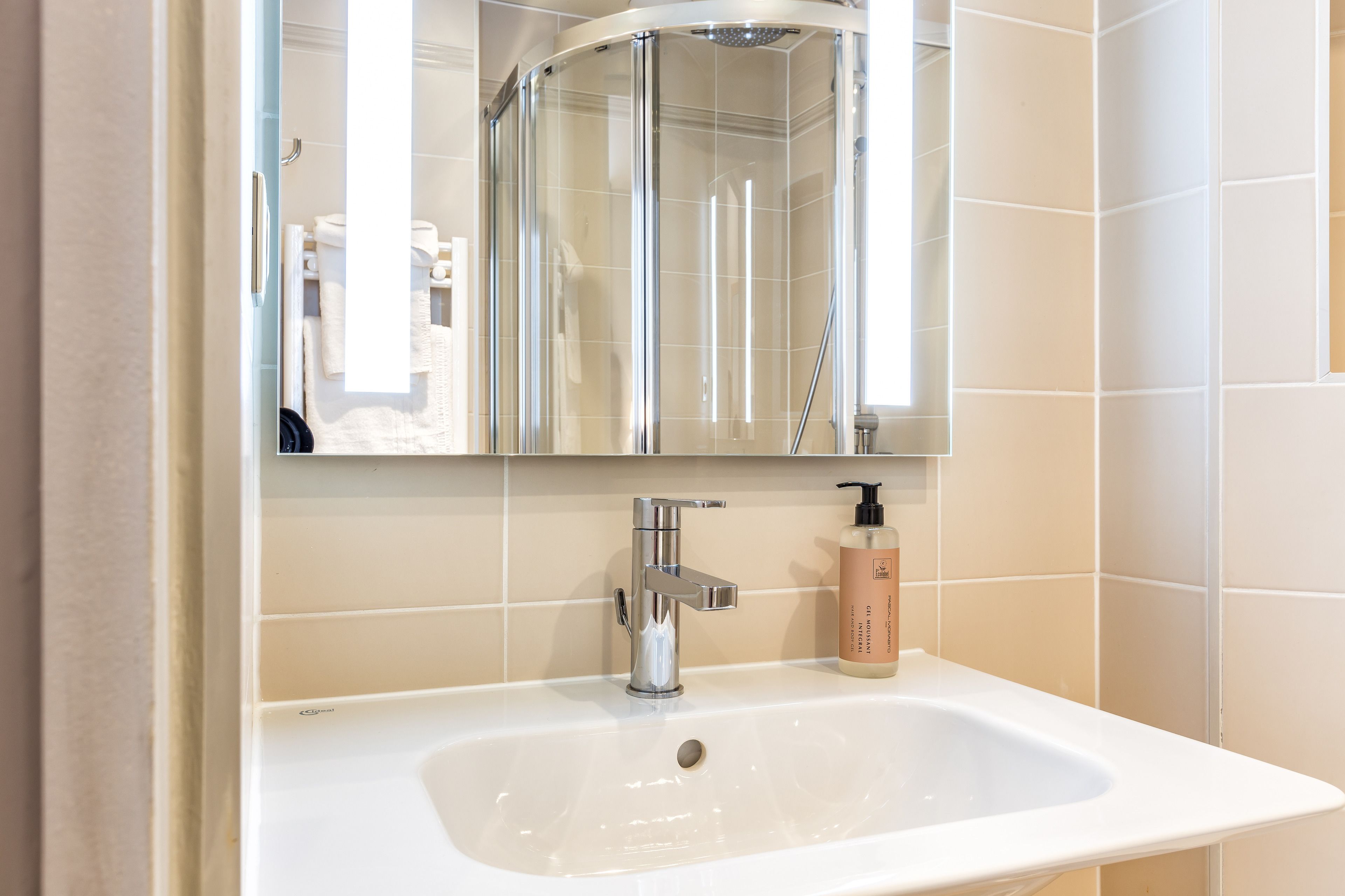 A bathroom with a white sink, chrome faucet, and a glass shower enclosure.