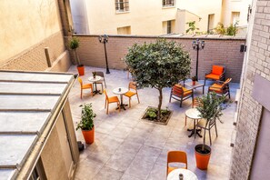 Eine Dachterrasse mit Sitzgelegenheiten im Freien, Topfpflanzen und Blick auf die Stadtlandschaft.