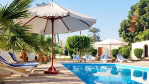 A pool area with lounge chairs and umbrellas. - Hotel Sheherazade (Luxor)