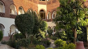 A courtyard with a brick building featuring arched windows and a tiled floor. - Hotel Sheherazade (Luxor)