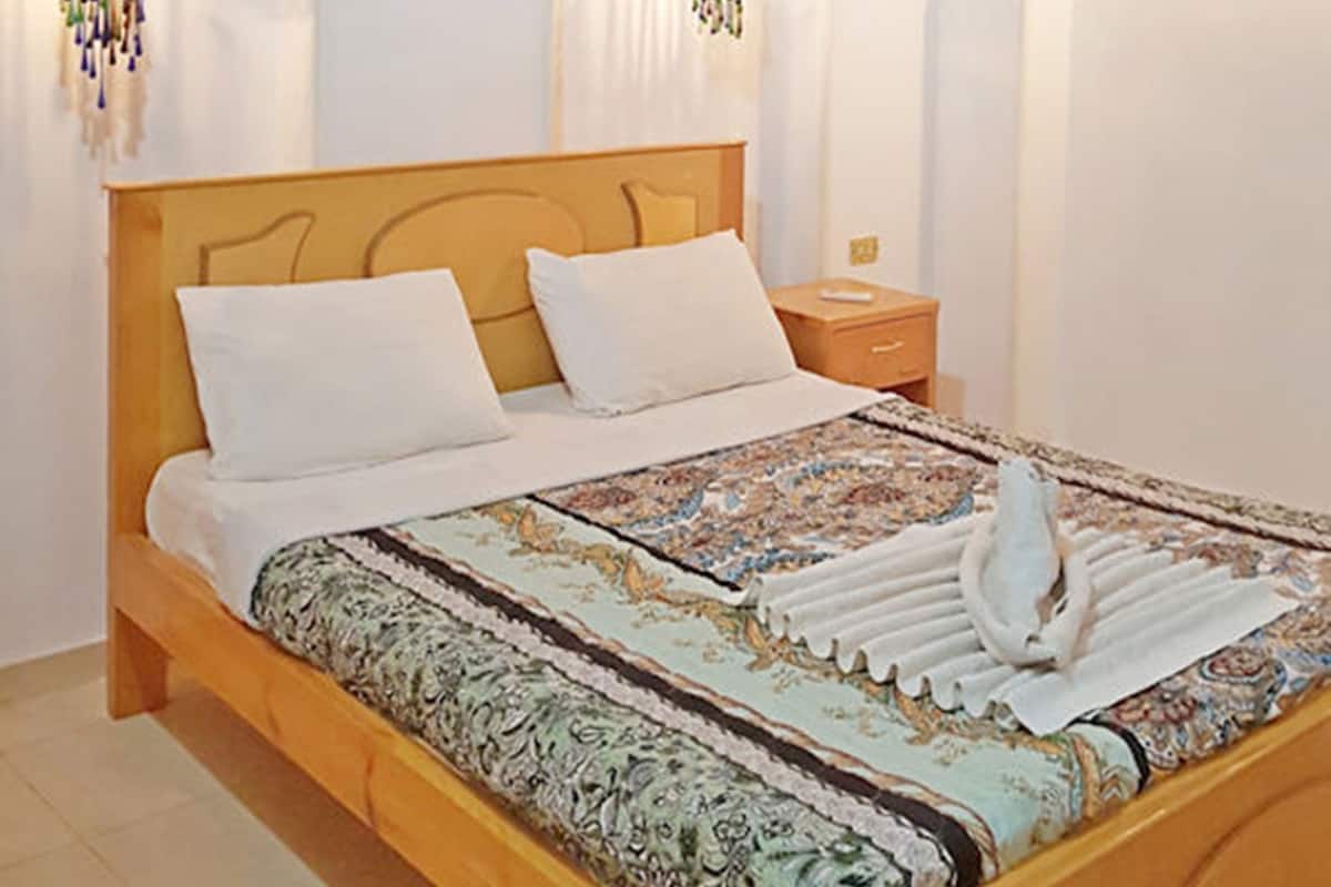 Un dormitorio con cama de madera, ropa de cama blanca y apliques decorativos.