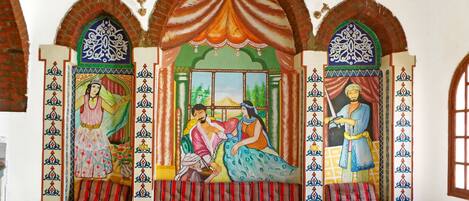 Una habitación de diseño tradicional, con un mural central que muestra figuras y un banco con cojines.