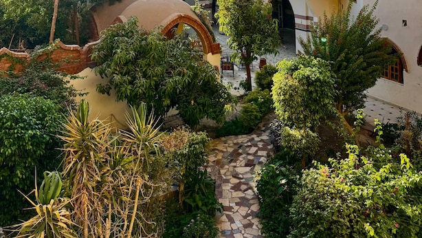 A courtyard with a brick building featuring arched windows and a tiled pathway. - Hotel Sheherazade (Luxor)