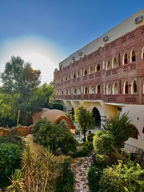 A courtyard with a brick building featuring arched windows and a tiled pathway. - Hotel Sheherazade (Luxor)