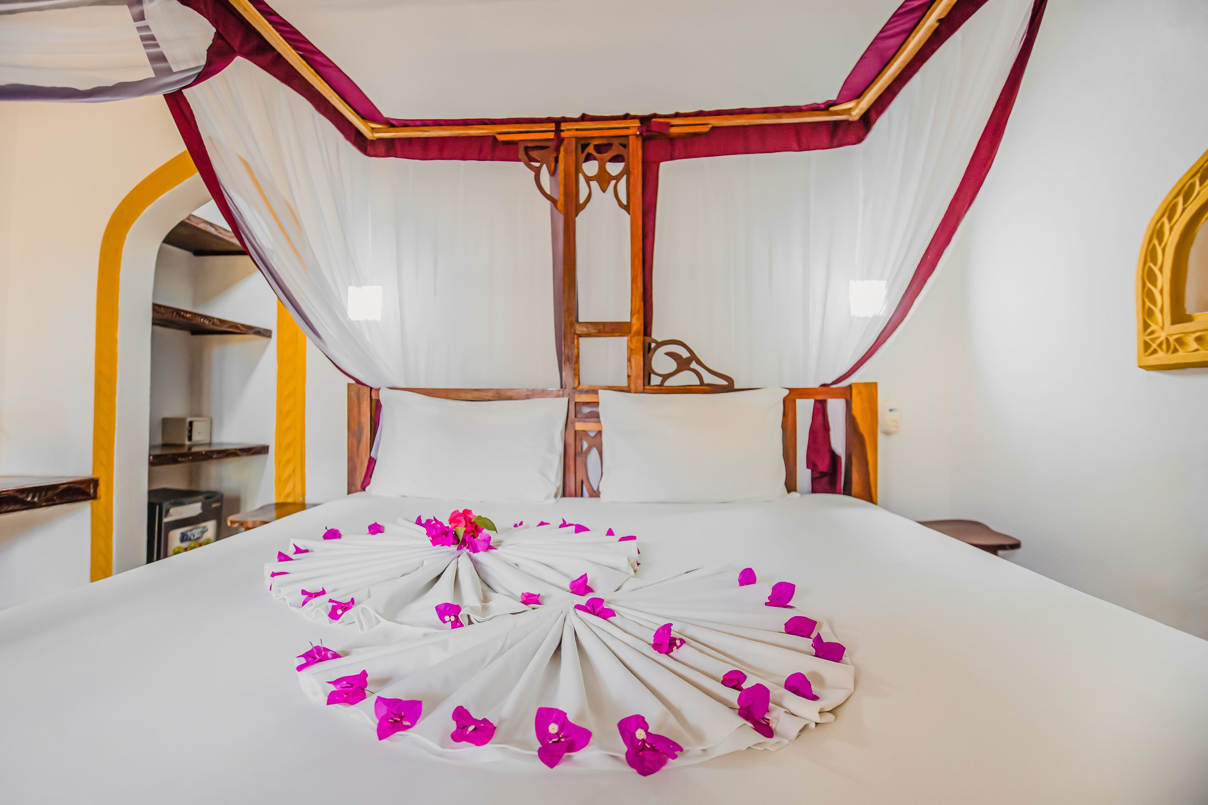 A bed with a canopy, a bedside table, and a mirror on the wall.
