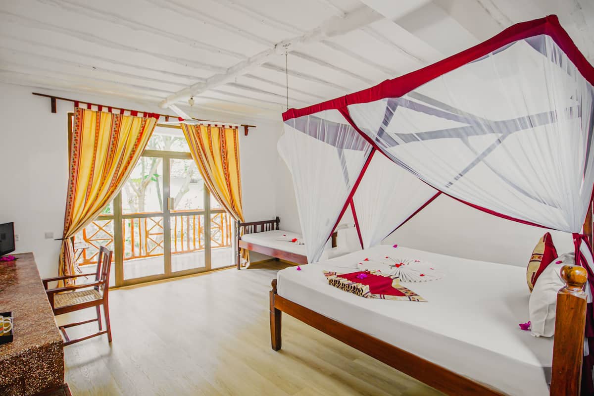 Ein Zimmer mit einem Bett, einem Schreibtisch und einem Stuhl. Ein Fenster mit Vorhängen ist vorhanden.
