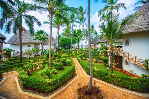 Un complexe hôtelier doté de bungalows aux toits de chaume, d’un jardin bien entretenu et d’un chemin clairement balisé.