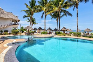 Una piscina al aire libre, sombrillas, sillones reclinables de piscina