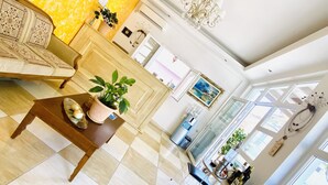 A spacious living area with a checkered floor, a sofa, a coffee table, and a dining table with chairs. There is a large window providing natural light and a painting on the wall. - Villa Antonis (Parga)