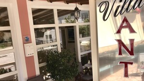 An outdoor seating area with wooden furniture and a potted plant. - Villa Antonis (Parga)