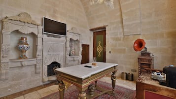 Una habitación con una mesa de mármol, chimenea, candelabro y un tocadiscos antiguo.