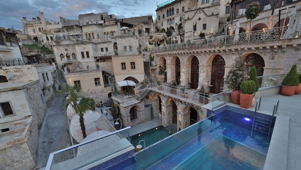 Zona de piscina con vistas a edificios históricos, una escalera y mobiliario exterior.