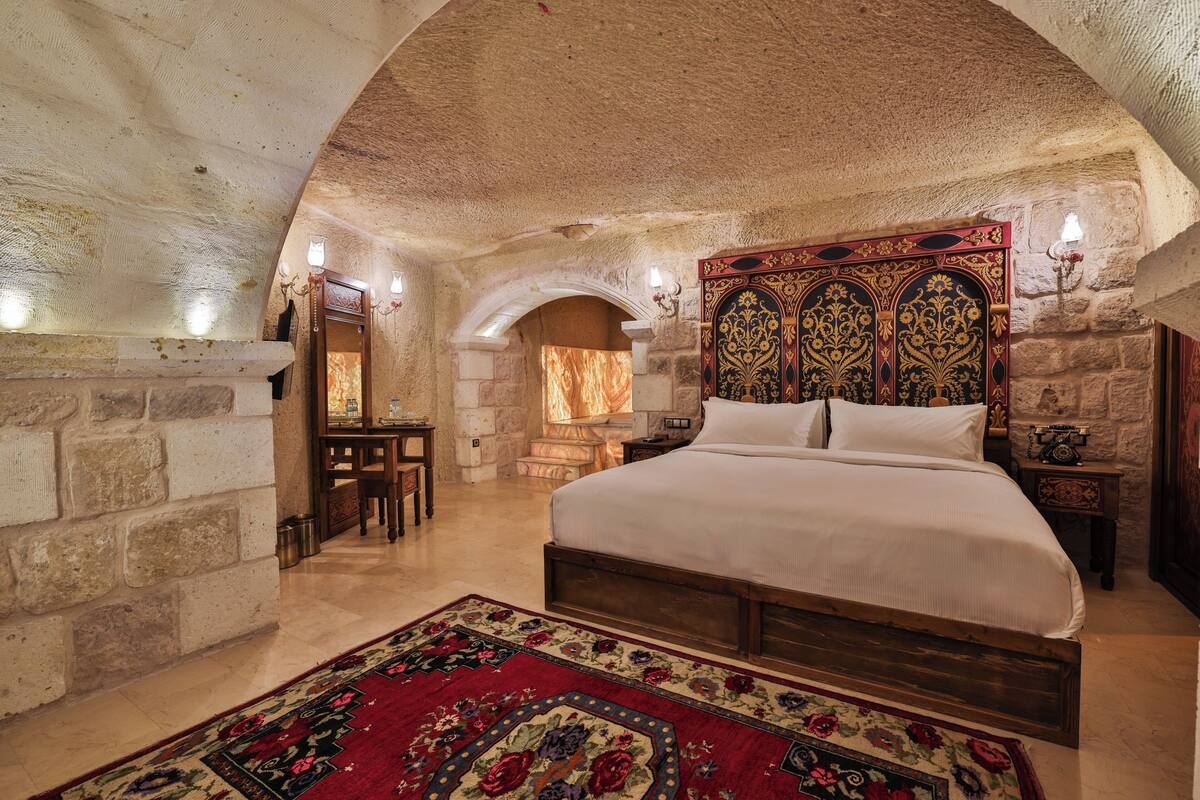 A bedroom with a large bed, stone walls, and a decorative headboard.