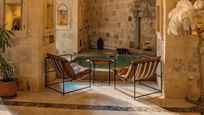 Una habitación con paredes de piedra, un candelabro, una chimenea y una mesa de billar.