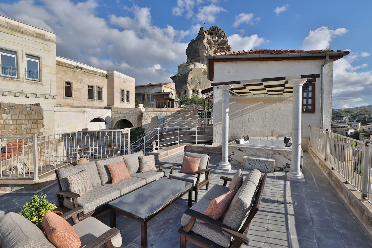 A rooftop terrace with outdoor seating, a view of a historic building, and a stone staircase.