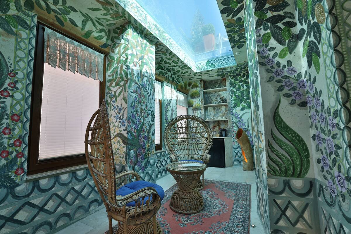 A room with patterned walls, a wicker chair, a small table, and a decorative vase.