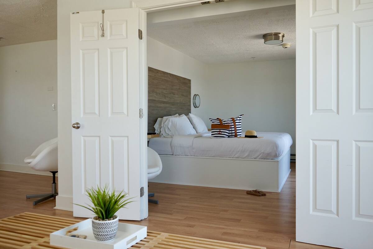 A bedroom with a bed, a chair, and a potted plant.
