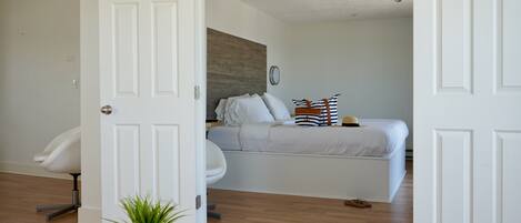 A bedroom with a bed, a chair, and a potted plant.