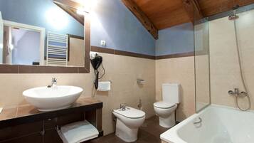 Un baño con un lavamanos grande, dos inodoros, una bañera y un espejo.