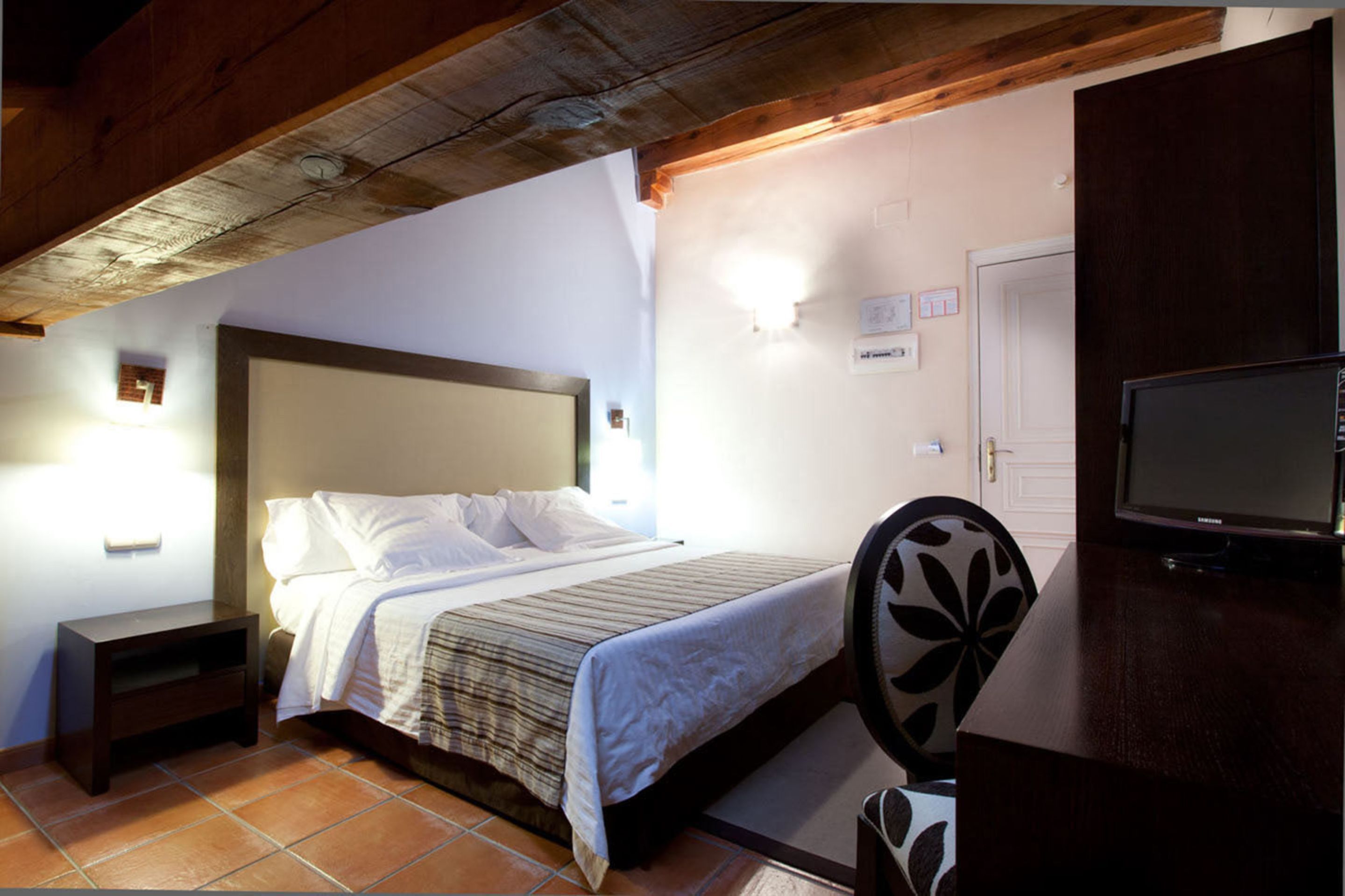 Une chambre à coucher avec un lit, une table de chevet, une télévision et une chaise.