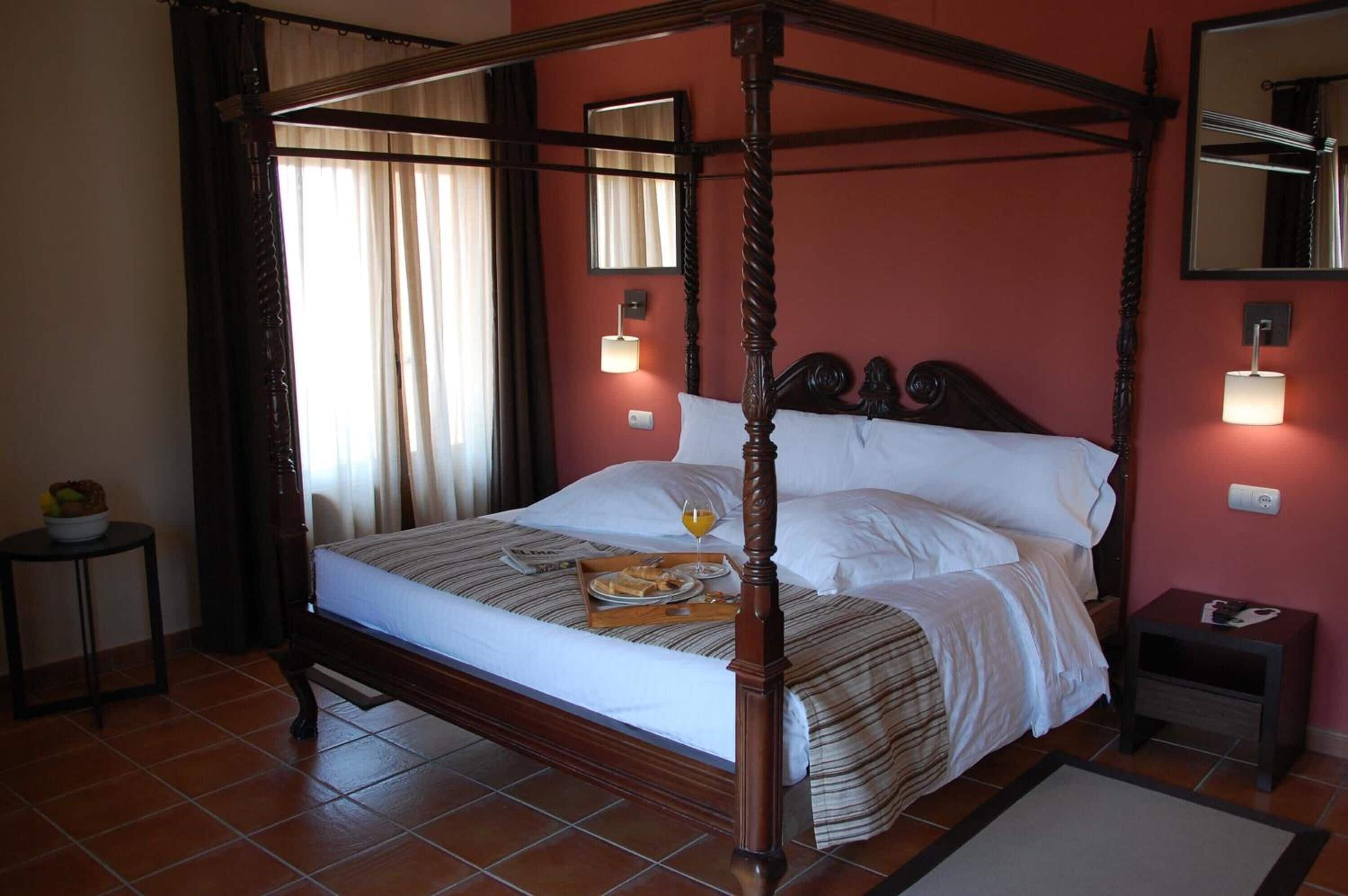 Un lit à baldaquin avec un plateau de petit-déjeuner, une table de chevet et une commode.
