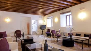 Una sala de estar moderna con techo de madera, una mesa de centro de vidrio y un sofá.