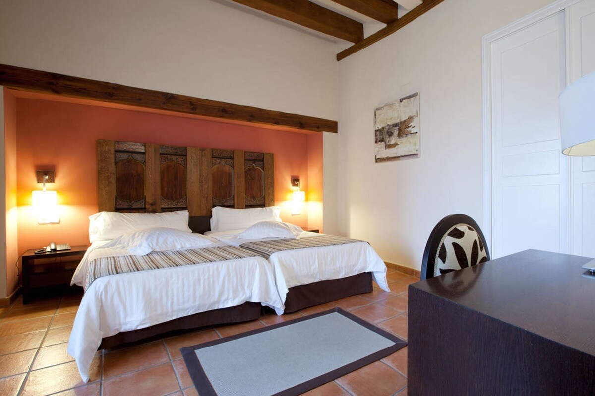 Un dormitorio con una cama doble, dos lámparas de noche, un escritorio y una silla.