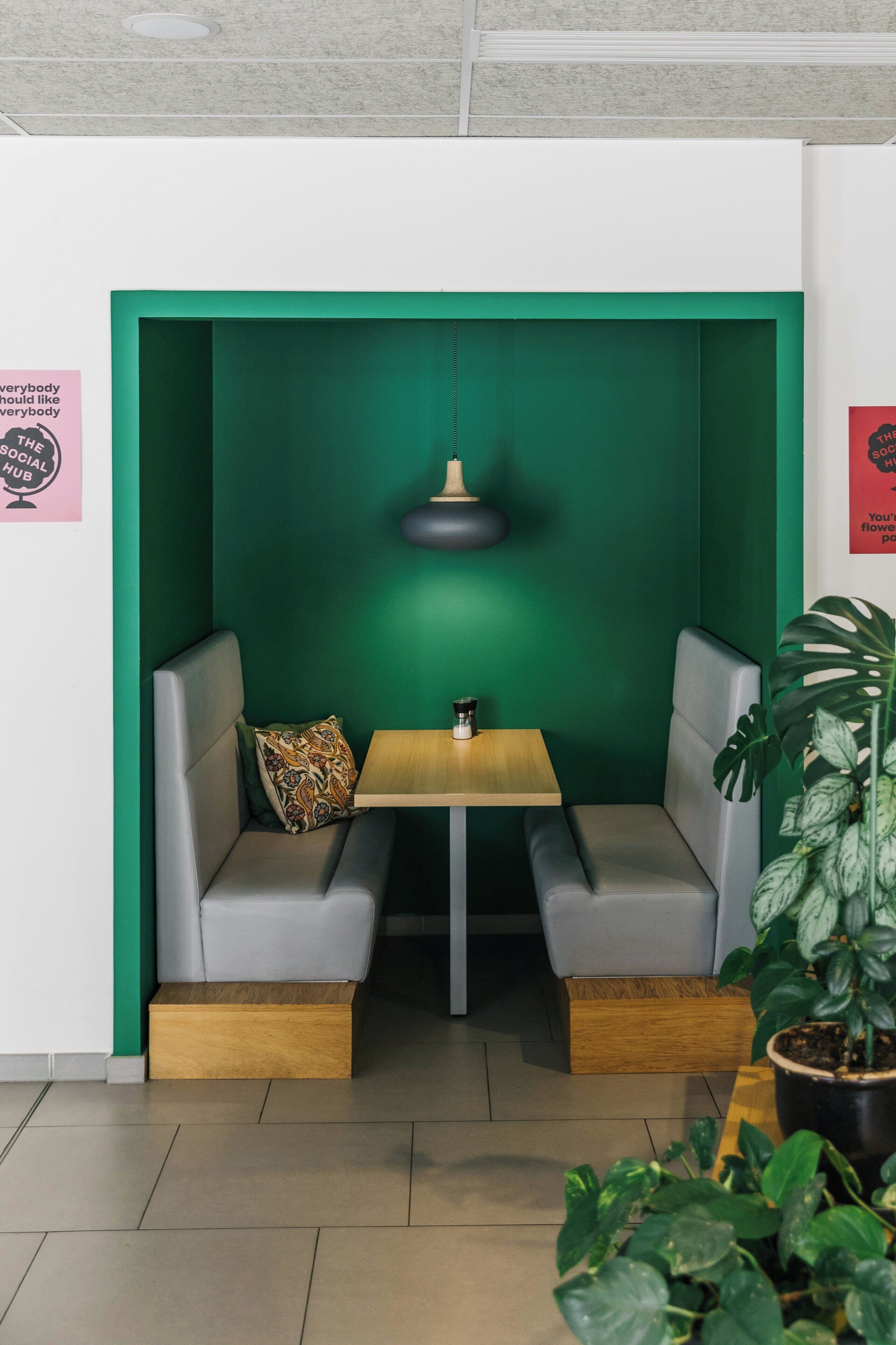 Un área de estar con una pared verde, una mesa y una lámpara colgante.