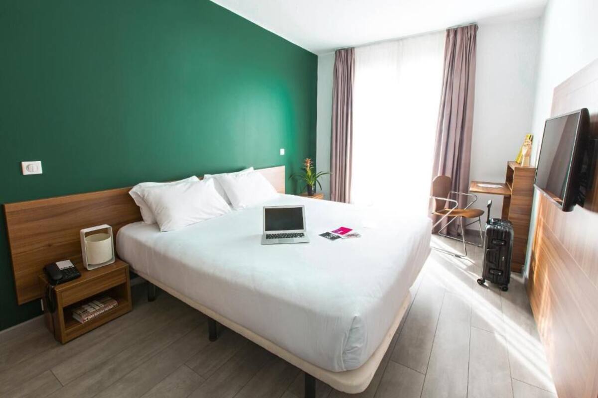 Une chambre d’hôtel équipée d’un lit, d’un bureau, d’une chaise, d’une télévision et d’un ordinateur portable.