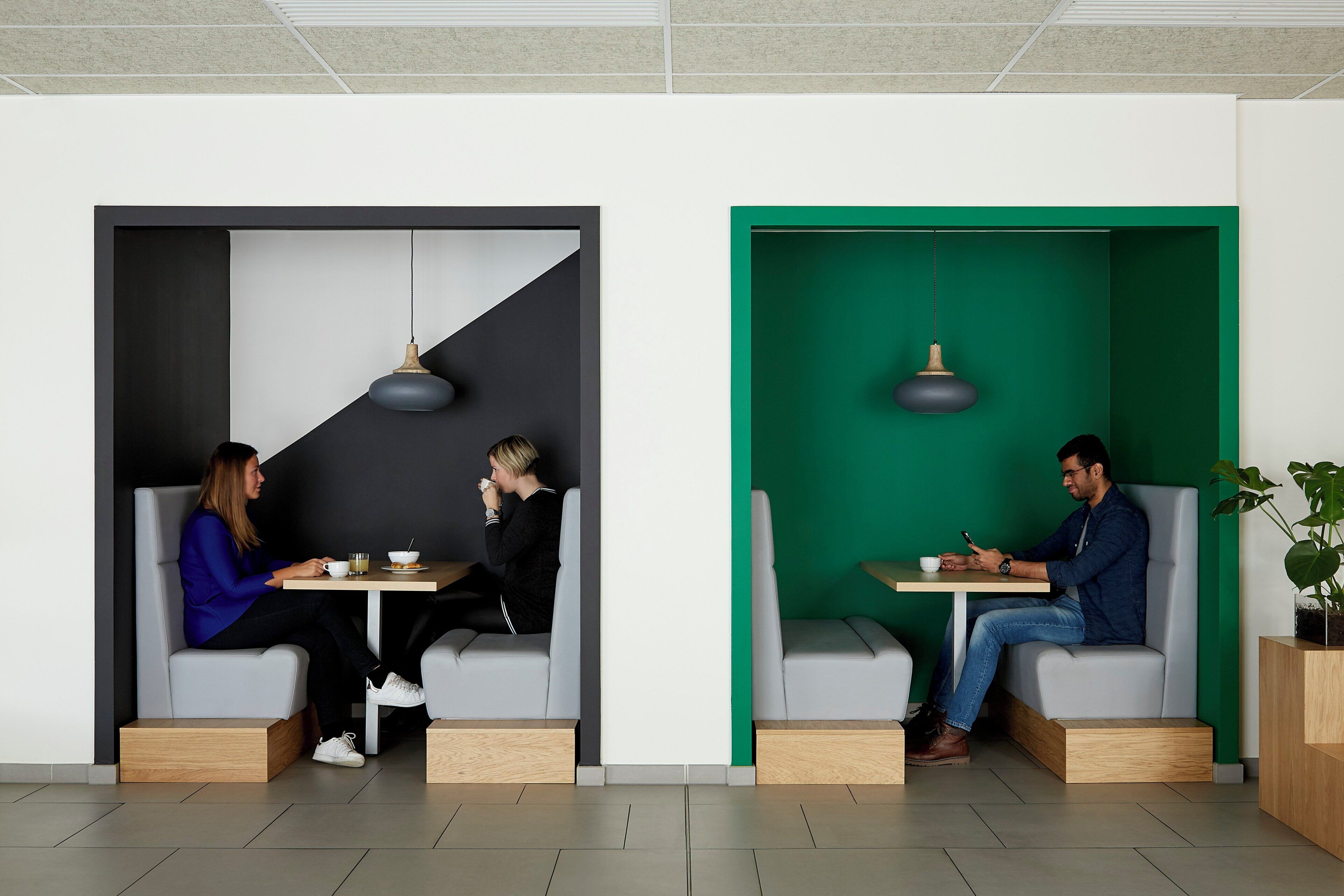 Un interior modern amb dues zones d'estar, cadascuna amb una taula i un llum penjant.