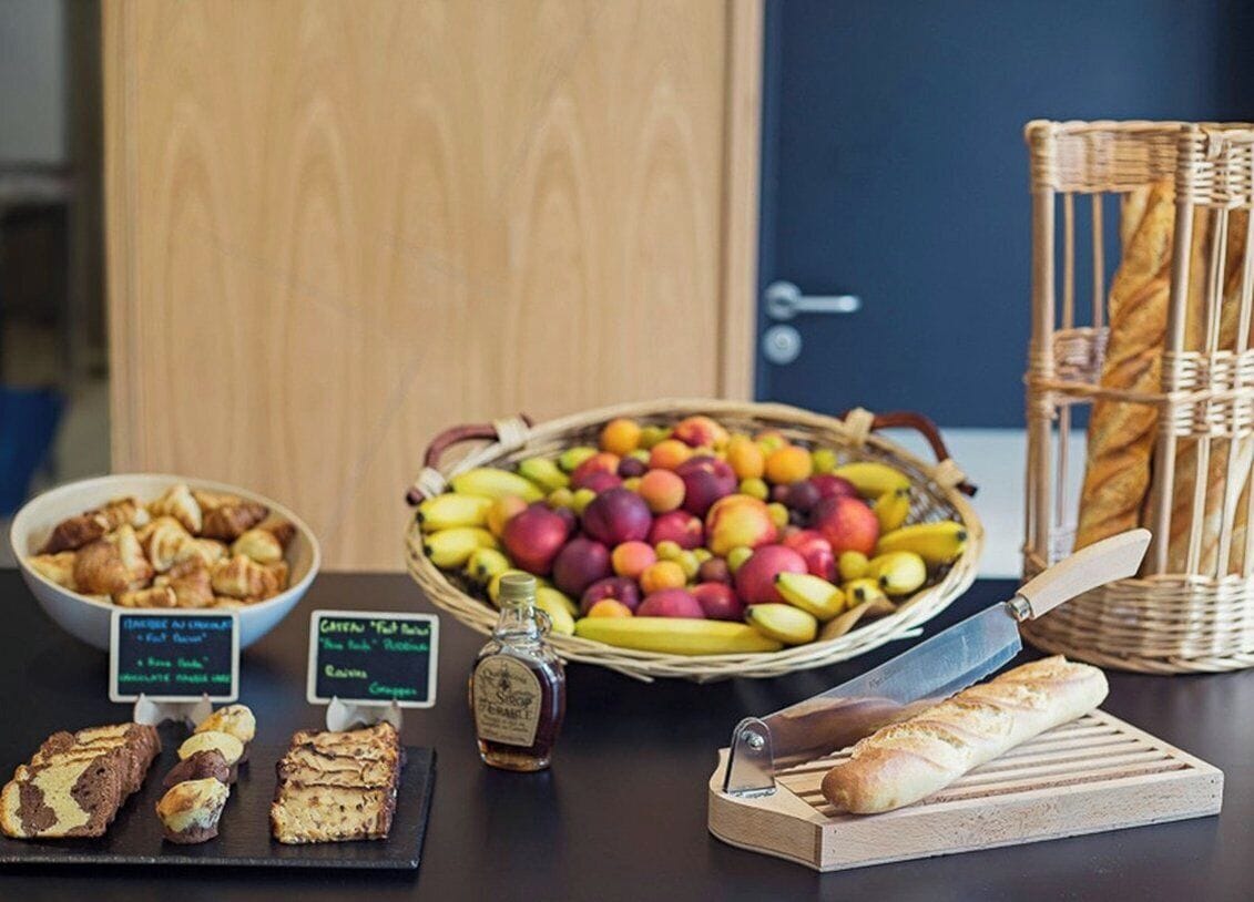 Un bufé de desayuno con pasteles, frutas y una botella de almíbar.