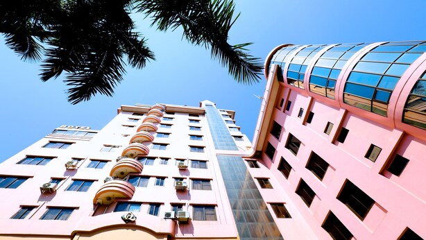 A multi-story hotel with a pink facade, balconies, and air conditioning units. - Queen's Park Hotel (Yangon)