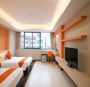 A hotel room with two beds, a desk, a chair, a TV, and a large window with a city view. - Eastern Hotel (Yangon)