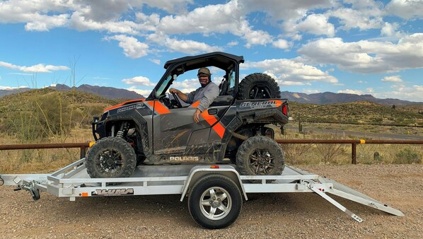 A Polaris 1000 ATV on a trailer with a desert landscape in the background.