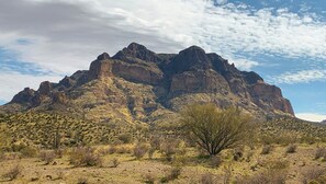 Eine gebirgige Landschaft mit spärlicher Vegetation und blauem Himmel.