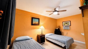 A hotel room with two single beds, a ceiling fan, a nightstand with a lamp, and two framed pictures on the wall. - Copper Mountain Motel (Superior)