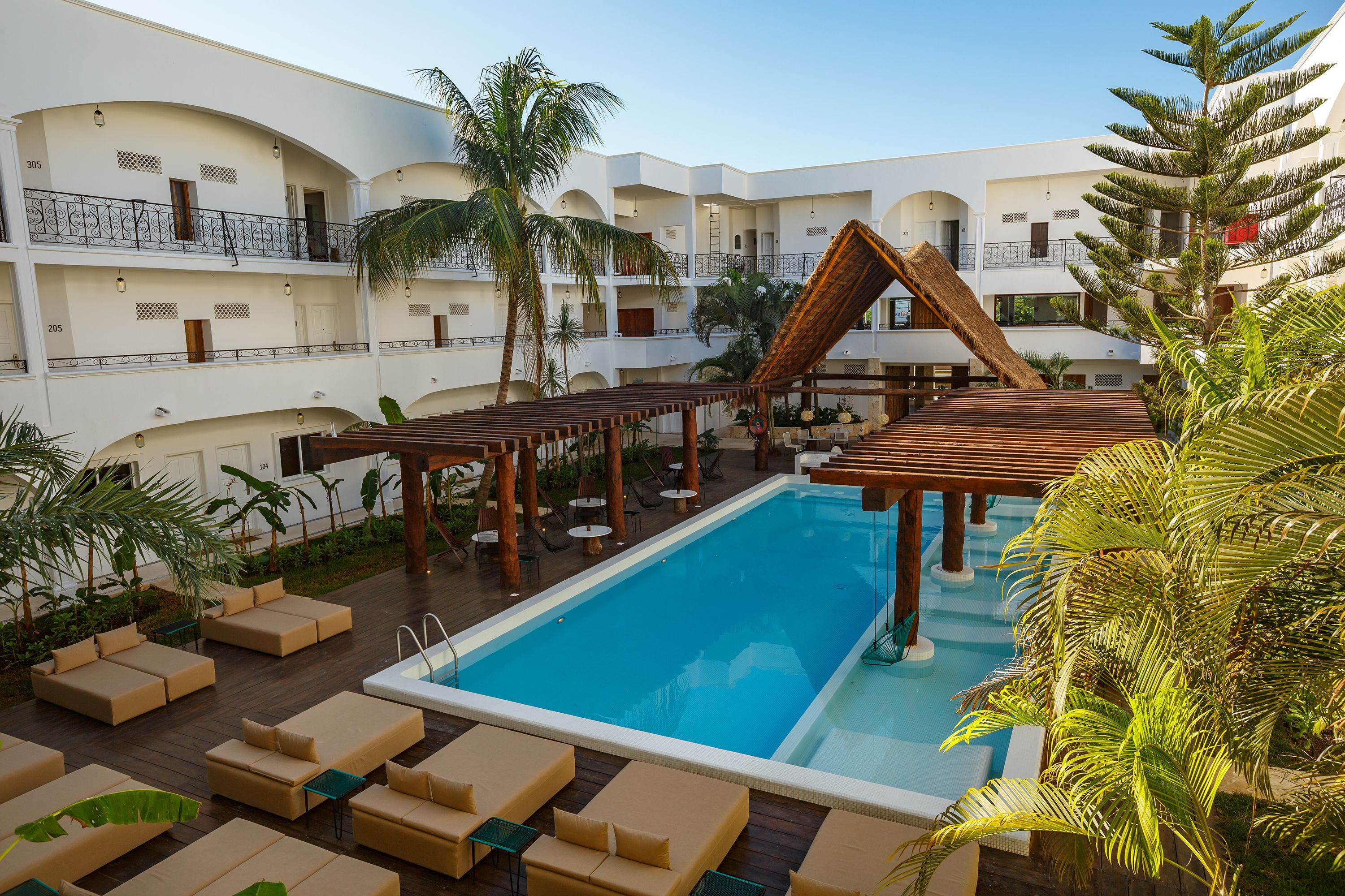 A pool area with lounge chairs and a wooden pergola.