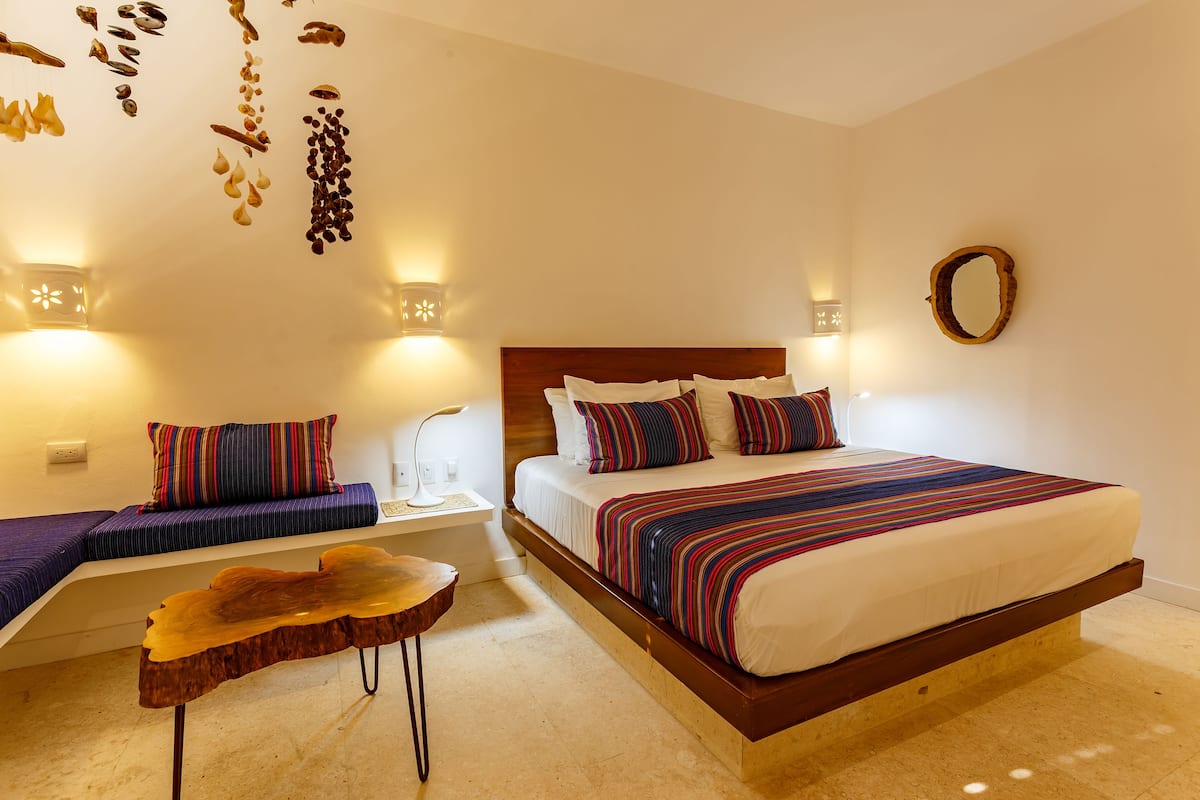 Ein Schlafzimmer mit einem großen Bett, einer Bank, einem Holztisch und Wandleuchten.