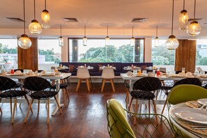 A restaurant with wooden floors, black and green chairs, and hanging pendant lights. - HM Playa del Carmen (Playa del Carmen)