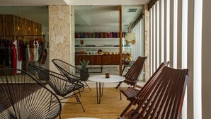 Un interior moderno con un área de estar que incluye sillas de metal y madera, una pequeña mesa redonda y una pared de piedra.