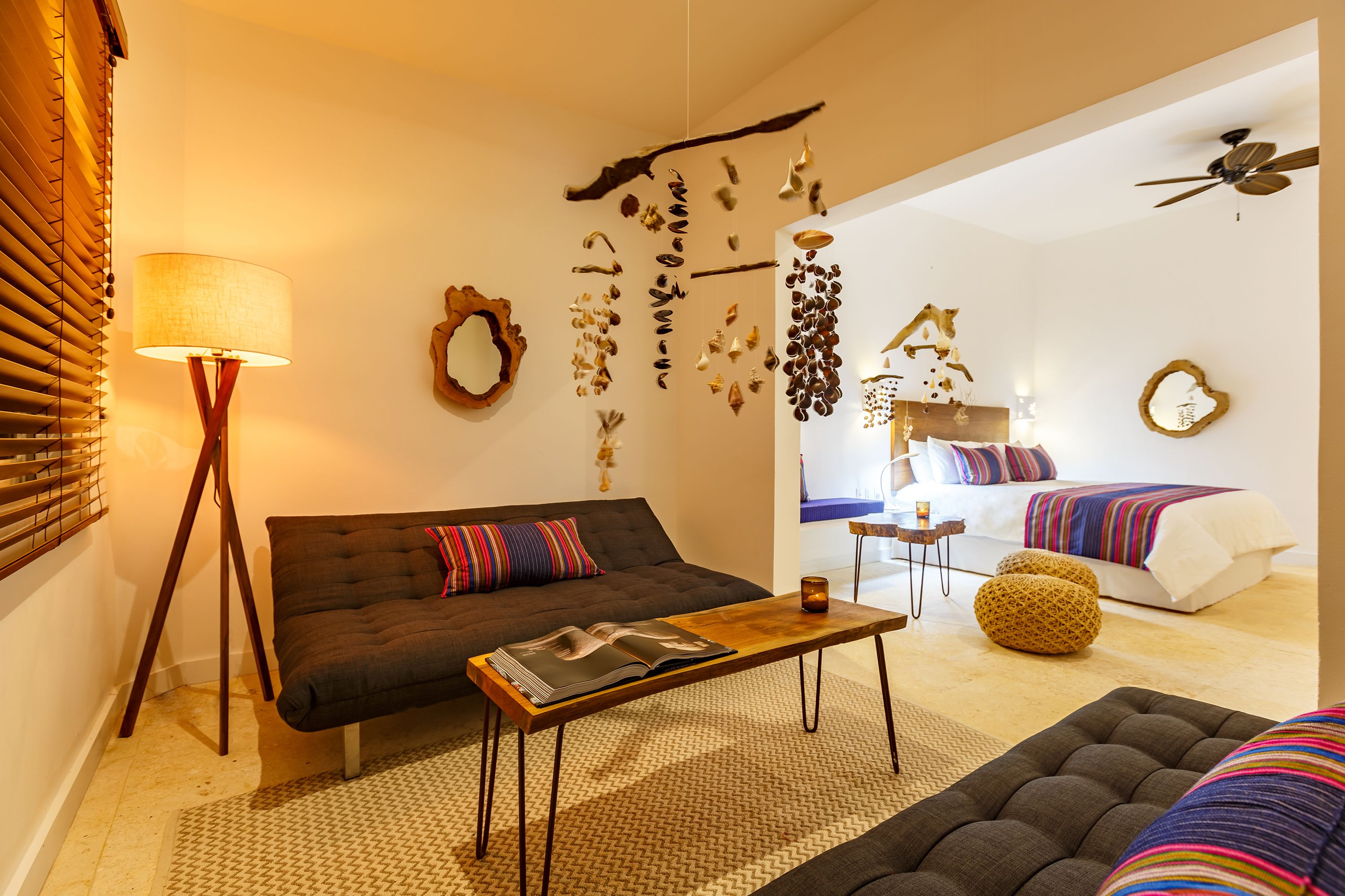 En moderne stue med sofa, sofabord og seng med stribet dyne.