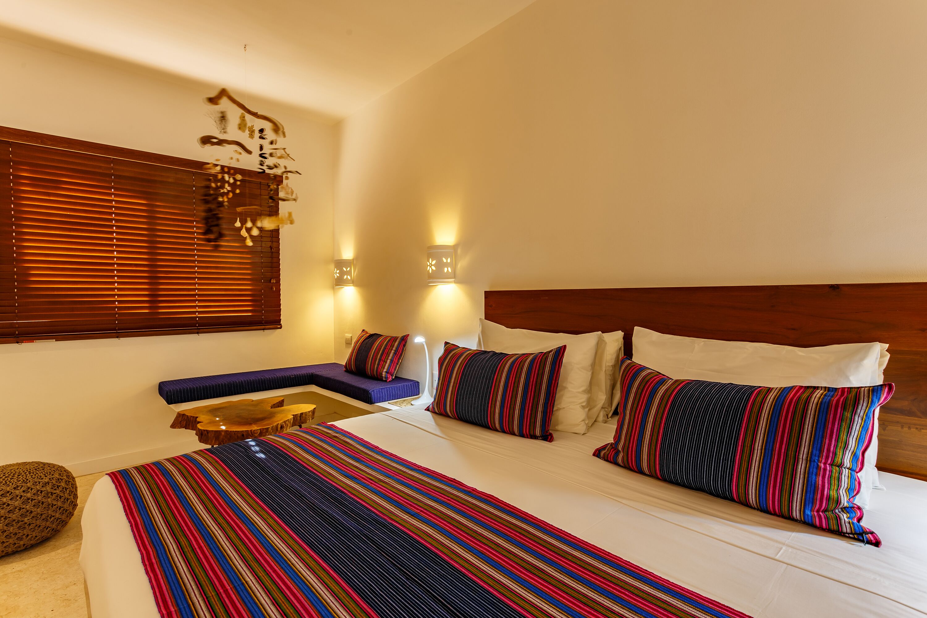 Een hotelkamer met een groot bed, een bankje en twee wandlampen.