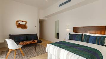 Una habitación de hotel moderna con una cama grande, un sofá, una mesa de centro de madera y una silla blanca.